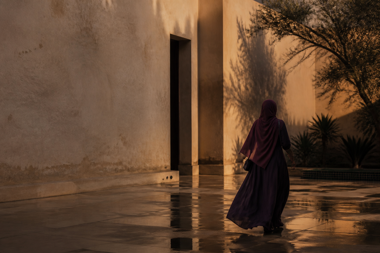 A woman walking through a rain-washed courtyard in late light.